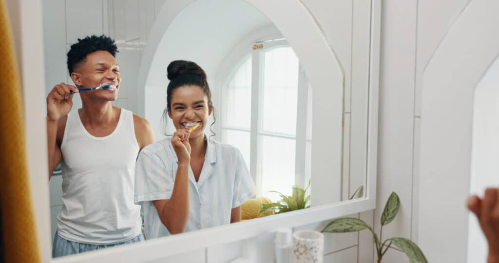 Two people brushing their teeth post teeth cleaning
